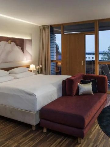 Elegantes Hotelzimmer mit großem Doppelbett und Balkon mit Aussicht auf die Natur