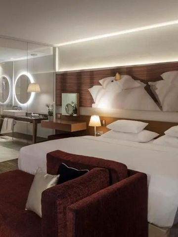 Modernes Hotelzimmer mit Doppelbett und stilvollem Badezimmer im Hintergrund