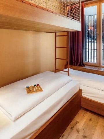 Gemütliches Hotelzimmer mit Etagenbetten und großen Fenstern mit Blick auf verschneite Landschaft