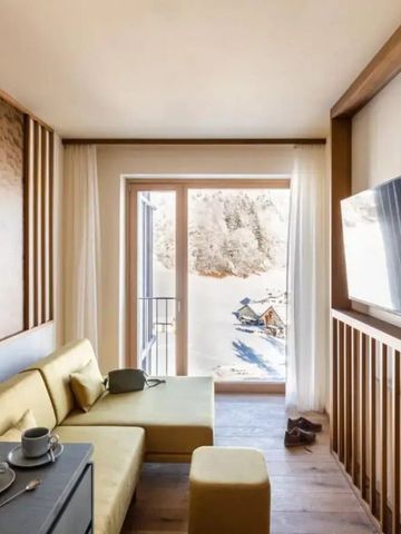 Helles Hotelzimmer mit moderner Einrichtung und Blick auf schneebedeckte Berge.