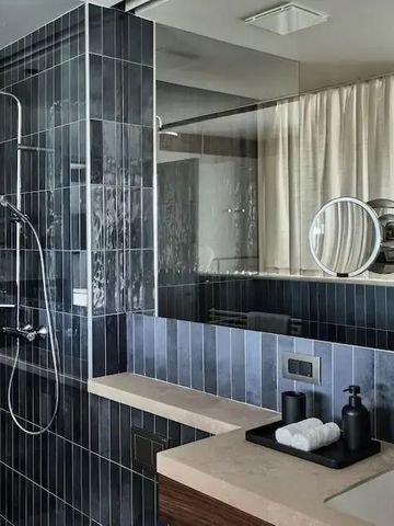 Modernes Badezimmerdesign mit dunklen Fliesen und großzügigem Spiegel