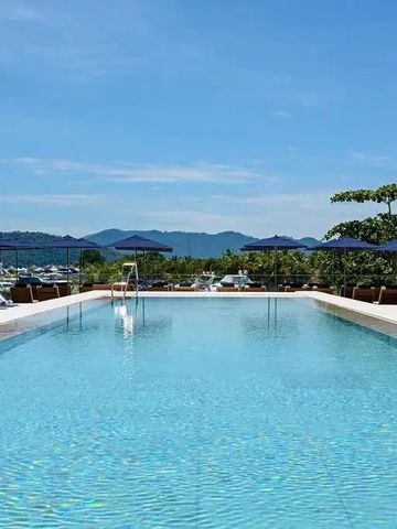 Infinity-Pool mit Blick auf das Meer und umliegende Berge unter blauem Himmel