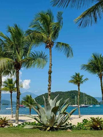 Tropischer Strand mit Palmen und Booten im Hintergrund