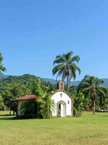 Kleine Kapelle in grüner, tropischer Landschaft bei klarem Himmel