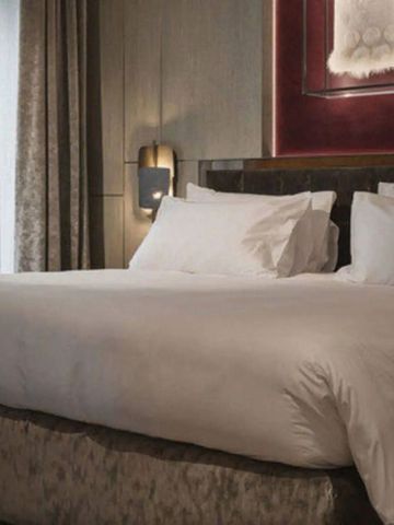 Gemütliches Kingsize-Bett mit hochwertiger Bettwäsche in elegantem Hotelzimmer