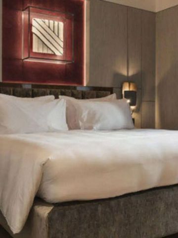 Luxuriöses Hotelbett mit hochwertiger Bettwäsche und Beleuchtung.