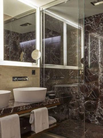 Stilvolles Badezimmer mit Marmordesign und großen Spiegeln.