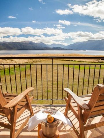 Holzbalkon mit Stühlen und Blick auf den See und die Berge bei sonnigem Wetter