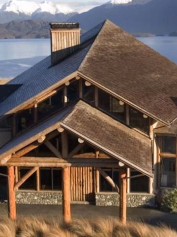 Architektonische Fassade der Fiordland Lodge vor einer Bergkulisse.