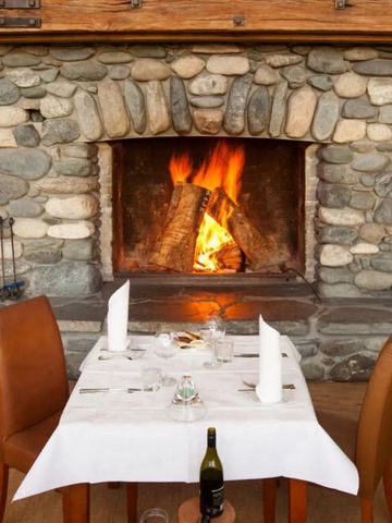 Gemütlicher Kamin aus Naturstein mit gedecktem Tisch im Vordergrund