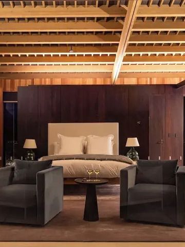 Luxuriöses Schlafzimmer mit Sesseln und Holzbalkendecke