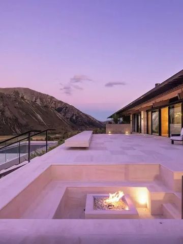 Terrasse mit Feuerstelle und Bergblick im Abendlicht.
