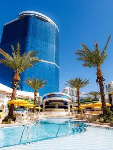 Belebter Poolbereich mit Palmen und hoch aufragendem Hotelgebäude im Hintergrund.