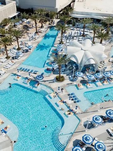 Großer Poolbereich mit blauen Sonnenschirmen und Palmen