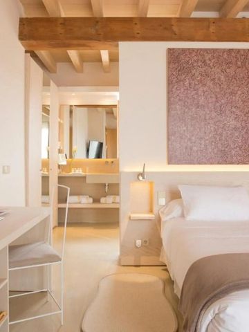 Innenraum mit Holzdachbalken, modernem Bett und eleganter Beleuchtung