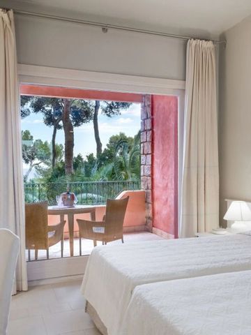 Modernes Hotelzimmer mit Blick auf Bäume und gemütlichem Balkon