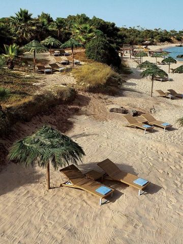 Ruhiger Sandstrand mit Liegestühlen und natürlichem Sonnenschutz im Forte Village Resort.