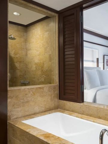 Badezimmer mit Marmorverkleidung und Blick in das angrenzende Schlafzimmer