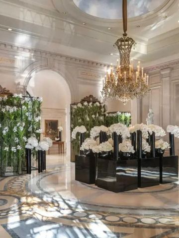 Elegante Lobby mit Marmorboden, großem Kronleuchter und dekorativen Blumenarrangements.