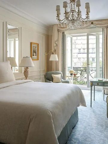 Helles Zimmer mit großem Bett, eleganten Möbeln und Zugang zu einem Balkon.