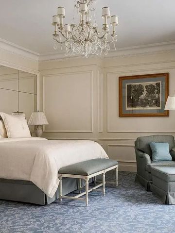 Luxuriös eingerichtetes Zimmer mit großem Bett, Spiegelwand und gemütlichem Sessel.