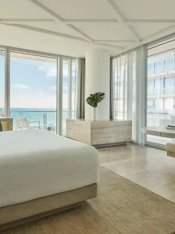 Helles Hotelzimmer mit Bett und Meerblick durchs Fenster