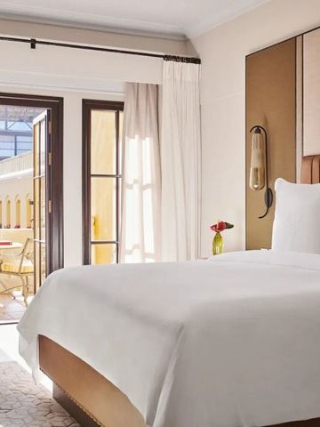 Helles Hotelzimmer mit Balkon und Blick auf den Innenhof.