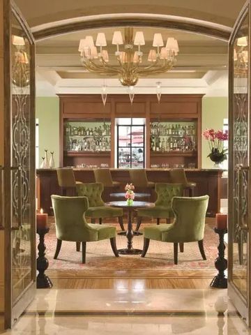 Stilvolle Hotelbar mit grünen Sesseln und einem beeindruckenden Kronleuchter