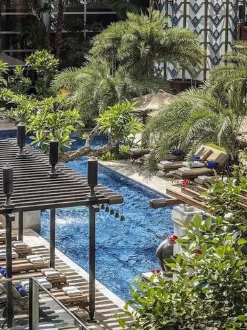 Eleganter Hotelpool umgeben von Pflanzen und Liegen