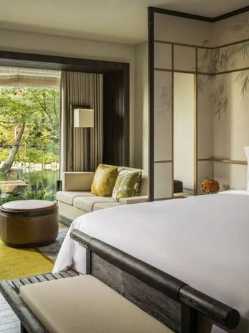 Luxuriöses Hotelzimmer mit großem Fenster und Ausblick auf den Garten.