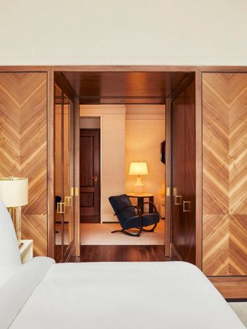 Zimmer mit Holzdetails und Blick in einen anderen Raum mit Sessel