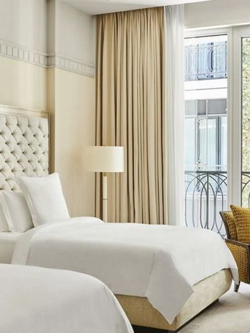 Helles Zimmer mit zwei Einzelbetten und großen Fenstern mit Balkonblick