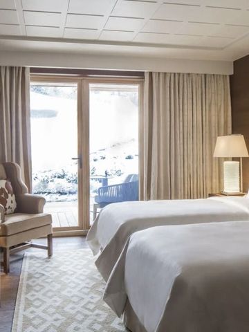 Modernes Zimmer mit zwei Einzelbetten und Zugang zu einem verschneiten Balkon.