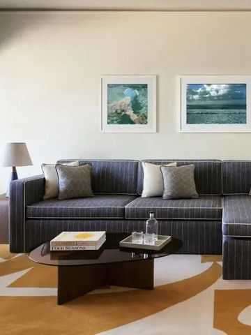 Stilvoll eingerichtetes Wohnzimmer in einer Hotelsuite mit modernem Sofa und Kunst an der Wand