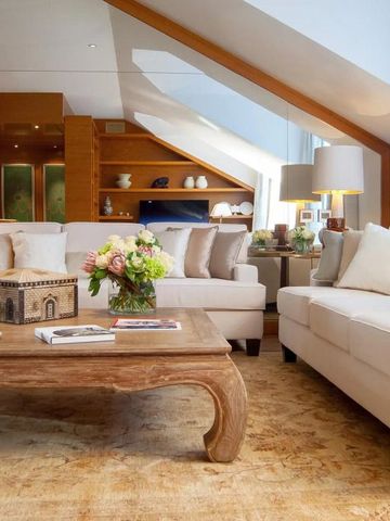 Geräumiges Wohnzimmer in warmer Atmosphäre mit Dachschräge, Sofas und Blumendekor