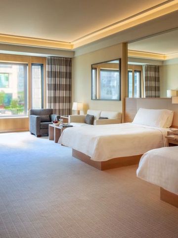 Elegantes Hotelzimmer mit zwei Betten und großer Fensteransicht