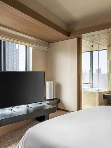 Zimmer mit Fernseher und großen Fenstern mit Stadtblick