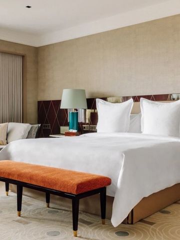 Modernes Hotelzimmer mit großem Bett, eleganter Bank und exklusiver Beleuchtung.