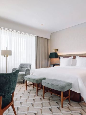 Großräumiges Zimmer mit stilvollem Bett, gemütlichen Sesseln und edlem Teppichdesign.