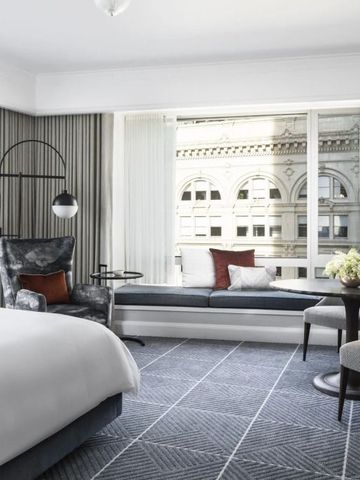 Helles Hotelzimmer mit gemütlicher Sitzecke und Blick auf die Stadt