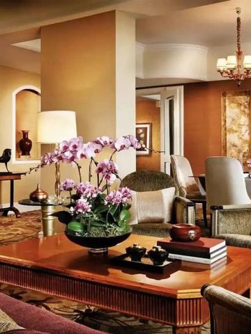 Luxuriöses Wohnzimmer in warmen Tönen mit eleganten Möbeln und Blumenarrangement.