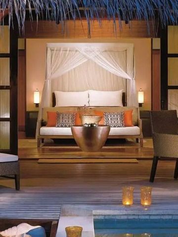 Entspannungsbereich im Freien mit Himmelbett am Pool umgeben von exotischer Dekoration