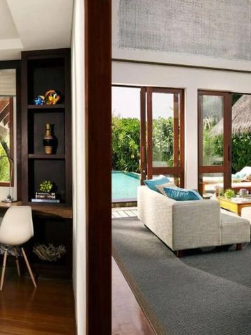 Zimmer mit gemütlicher Sitzecke und Ausblick auf tropischen Garten und Pool