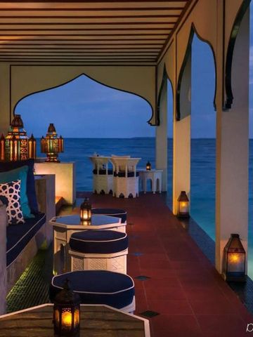 Romantische Terrasse am Meer mit beleuchteter Dekoration bei Abenddämmerung