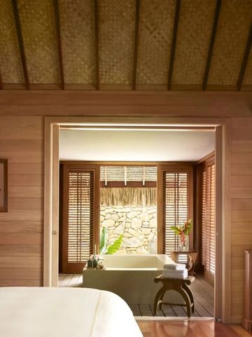Luxuriöses Badezimmer mit Holzwänden und Badewanne im Four Seasons Resort Bora Bora