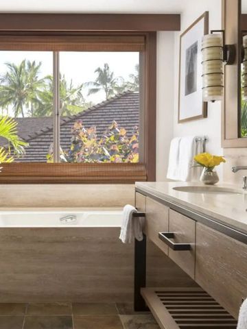 Badezimmer mit Badewanne und Aussicht auf Palmen und Dachlandschaft