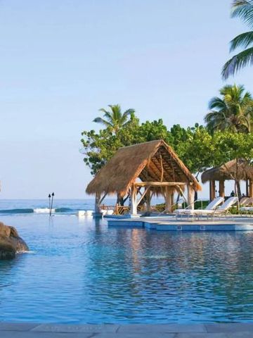 Palmengesäumter Poolbereich mit Strandhütten