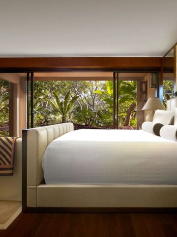 Geräumiges Hotelzimmer mit großem Bett und Blick auf tropischen Garten