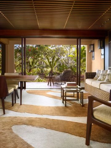 Eleganter Wohnbereich mit Holzmöbeln und Blick auf tropischen Garten