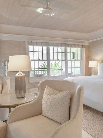 Schlafzimmer mit eleganter Einrichtung, Sitzbereich und großen Fenstern